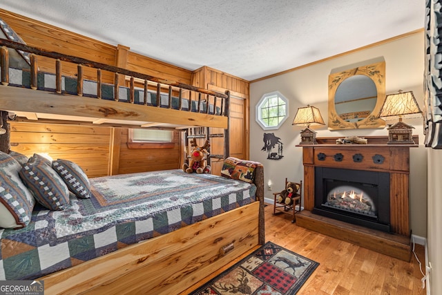 259 Eagle Chase Cir, Dillard, GA 30537 - bedroom with wood finished floors, crown molding, a lit fireplace, a textured ceiling, and baseboards