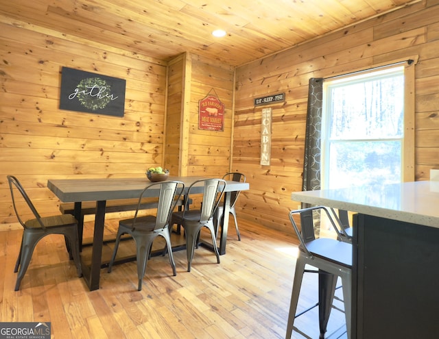 dining area with wooden ceiling, wooden walls, and light wood-style floors
