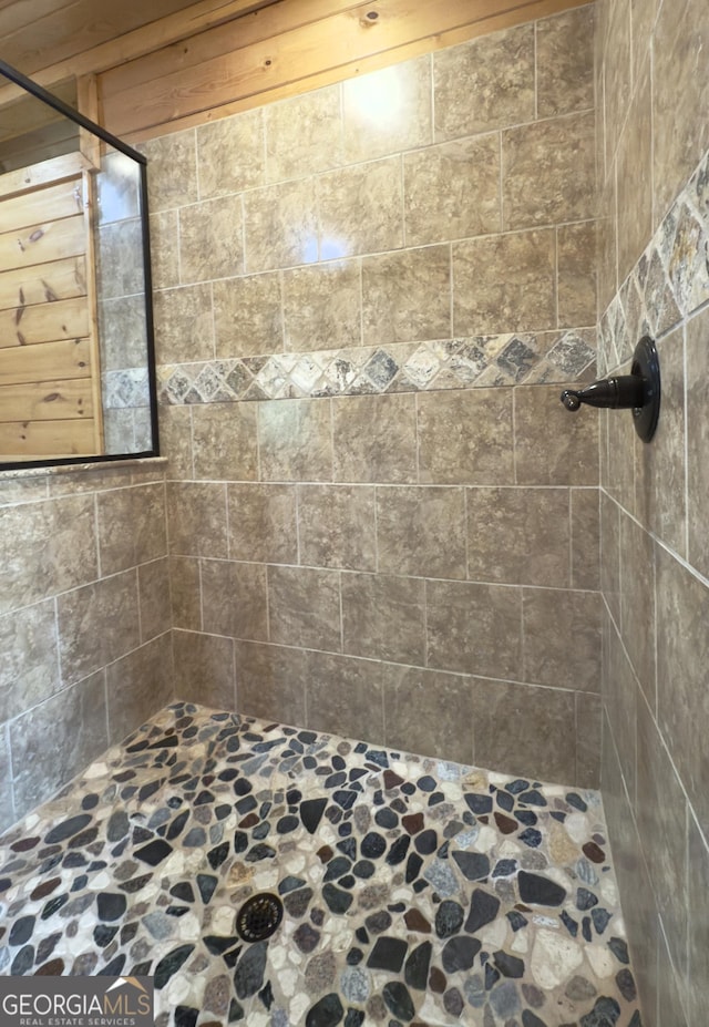 full bath featuring stone floors and a shower stall