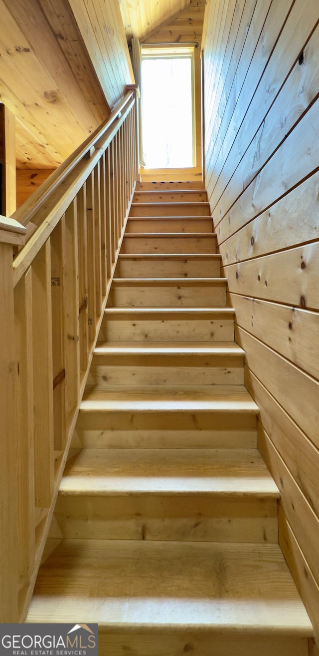 stairway featuring wooden walls, wood ceiling, and vaulted ceiling