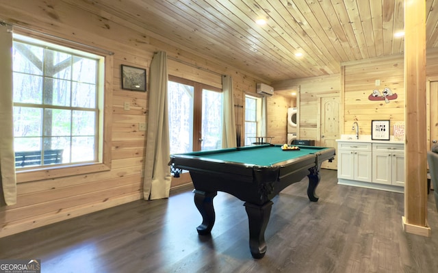 recreation room with wood walls, stacked washer / drying machine, wooden ceiling, healthy amount of natural light, and dark wood-style flooring
