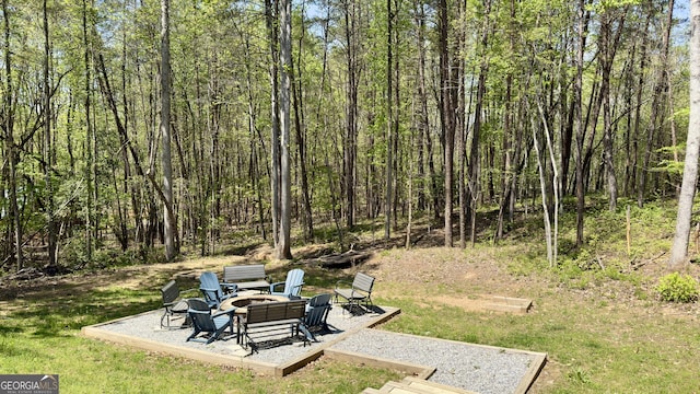 view of yard featuring a fire pit, a patio, and a forest view