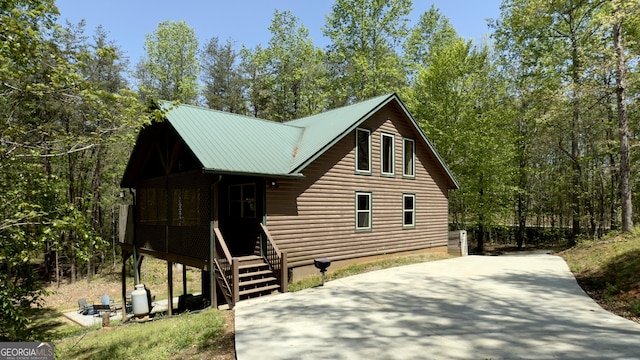 chalet / cabin featuring driveway, faux log siding, and metal roof