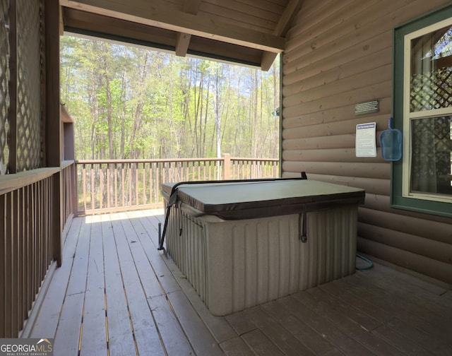 deck with a hot tub and a forest view