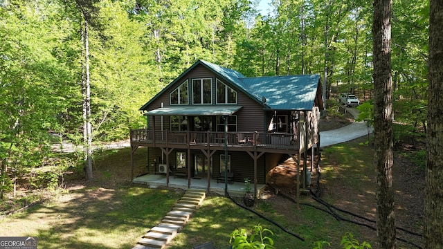 rear view of house with a wooden deck, a patio, metal roof, and a view of trees