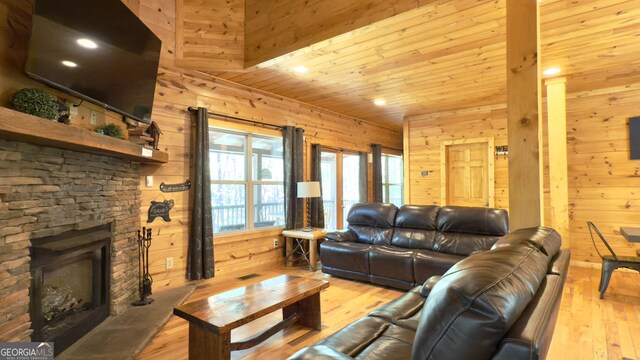 living room with wooden walls, a stone fireplace, light wood-type flooring, recessed lighting, and wooden ceiling