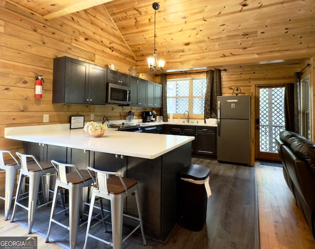 kitchen with appliances with stainless steel finishes, vaulted ceiling, plenty of natural light, a peninsula, and wooden ceiling