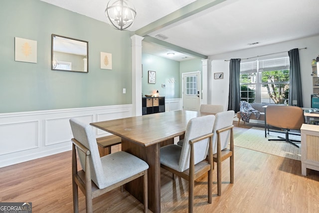4104 Glenaire Way NW, Acworth, GA 30101 - dining room featuring decorative columns, light wood-type flooring, wainscoting, a decorative wall, and a chandelier