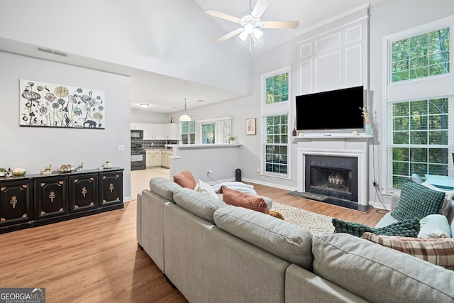 4104 Glenaire Way NW, Acworth, GA 30101 - living area featuring light wood-style flooring, a ceiling fan, a fireplace with raised hearth, and lofted ceiling