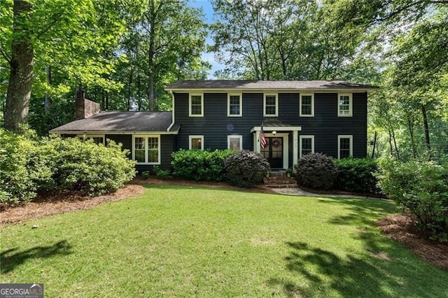 colonial inspired home with a front yard and a chimney