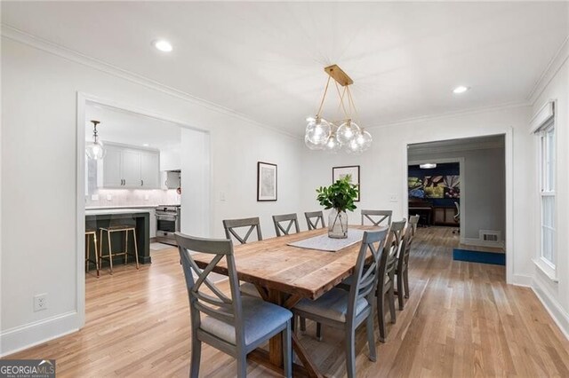 dining room featuring light wood-type flooring, ornamental molding, a chandelier, baseboards, and recessed lighting