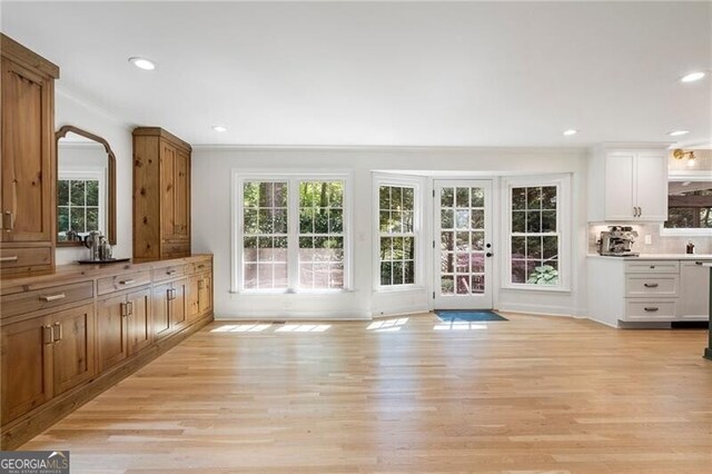 entryway with light wood finished floors, healthy amount of natural light, recessed lighting, and crown molding