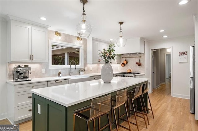 kitchen with a sink, green cabinets, a center island, backsplash, and white cabinetry