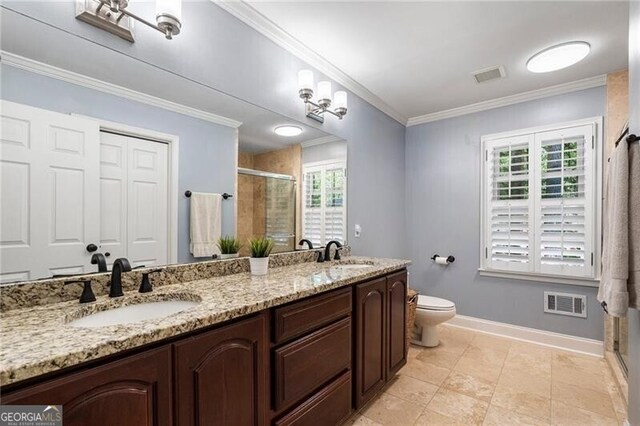 bathroom featuring a shower stall, double vanity, ornamental molding, baseboards, and toilet