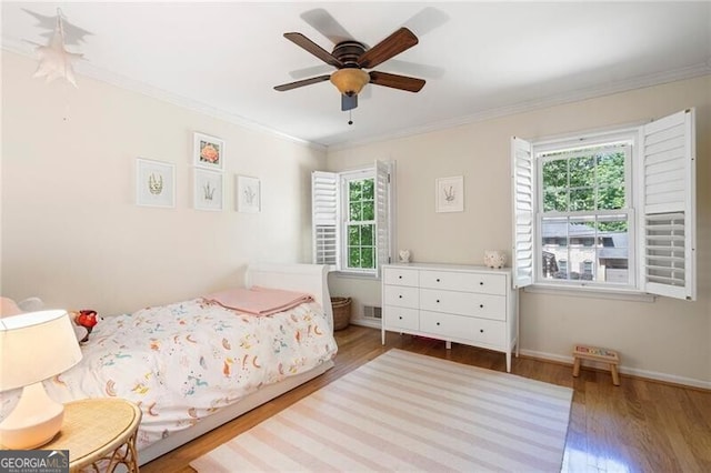 bedroom with wood finished floors, multiple windows, ornamental molding, baseboards, and ceiling fan