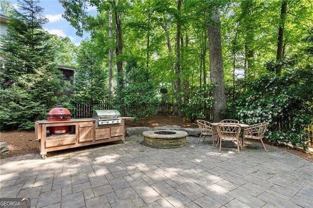 view of patio / terrace featuring a grill, an outdoor fire pit, exterior kitchen, and fence