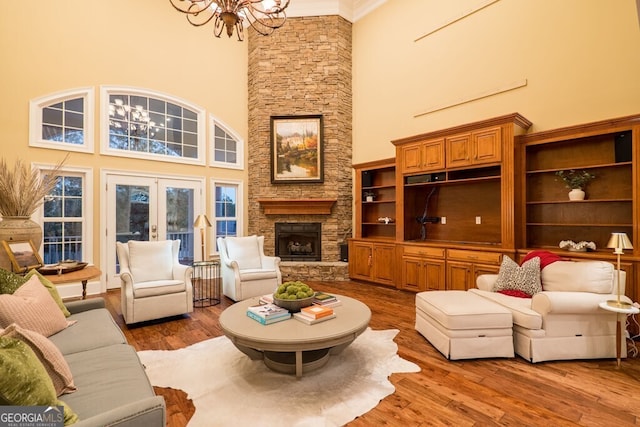 4345 Spring Branch Cir, Valdosta, GA 31601 - living room with a towering ceiling, a chandelier, wood finished floors, a stone fireplace, and french doors