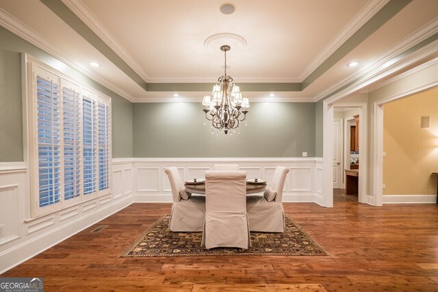 4345 Spring Branch Cir, Valdosta, GA 31601 - dining area featuring a chandelier, a decorative wall, dark wood-type flooring, a raised ceiling, and ornamental molding
