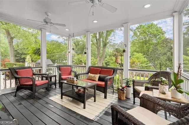 sunroom / solarium featuring ceiling fan, an outdoor living space, and view of wooded area
