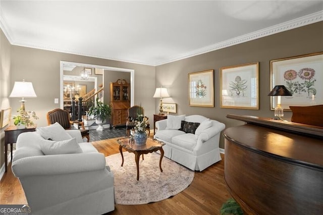 living area with a chandelier, crown molding, and wood finished floors