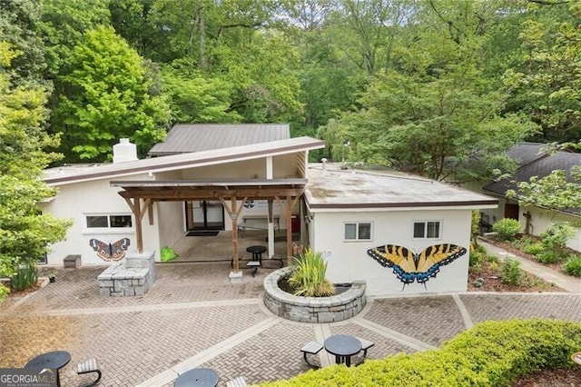 back of house featuring a patio, stucco siding, and a chimney