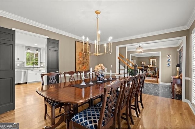 dining space featuring a chandelier, light wood-style floors, ornamental molding, baseboards, and stairway