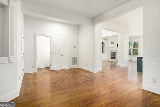 unfurnished living room featuring wood finished floors, baseboards, and a fireplace