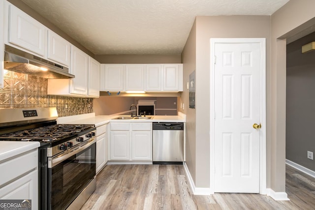 3001 Majestic Park Ct, Duluth, GA 30096 - kitchen with appliances with stainless steel finishes, under cabinet range hood, light wood-style floors, white cabinetry, and decorative backsplash