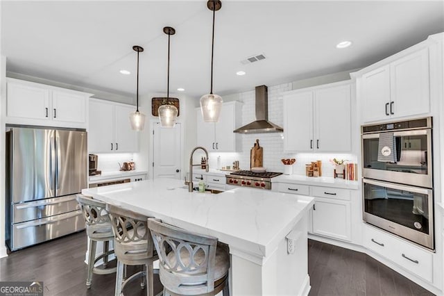 6150 Bridge Fair Rd, Cumming, GA 30028 - kitchen featuring appliances with stainless steel finishes, wall chimney exhaust hood, a sink, a center island with sink, and decorative backsplash