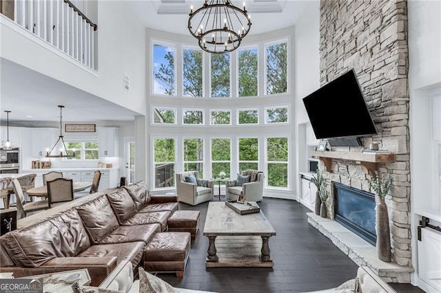 6150 Bridge Fair Rd, Cumming, GA 30028 - living area with a chandelier, a towering ceiling, dark wood finished floors, and a stone fireplace