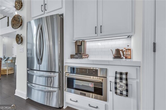 6150 Bridge Fair Rd, Cumming, GA 30028 - kitchen featuring stainless steel appliances, tasteful backsplash, light countertops, white cabinets, and dark wood-style floors