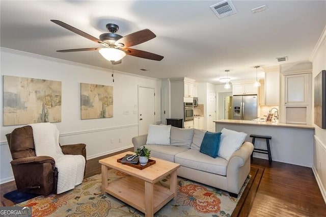 living area featuring ceiling fan, ornamental molding, dark wood-style floors, and baseboards