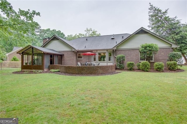 view of front of home with brick siding, a sunroom, and a chimney