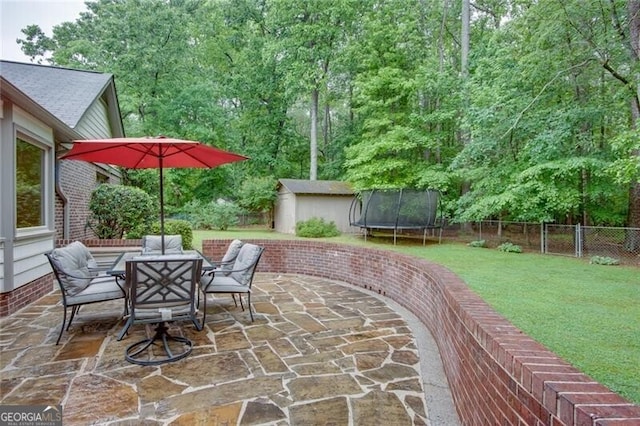 view of patio / terrace featuring a trampoline, a storage unit, an outdoor structure, and outdoor dining space