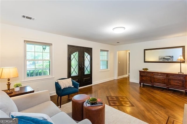 living area with healthy amount of natural light, wood finished floors, french doors, and baseboards