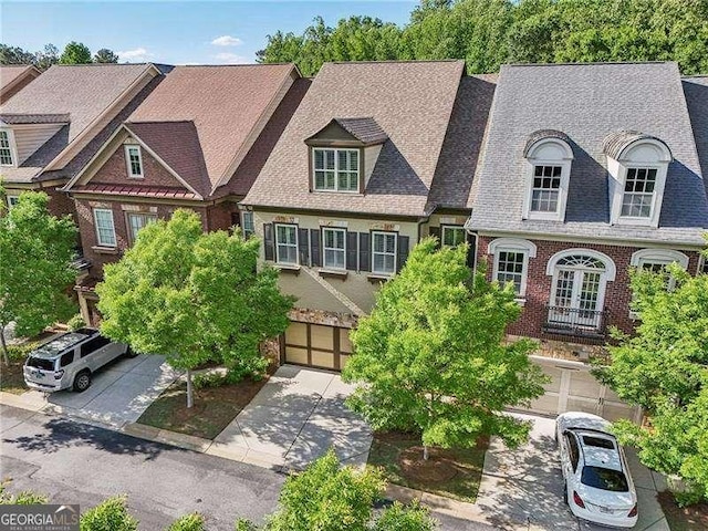 view of front of house featuring roof with shingles, a garage, and driveway