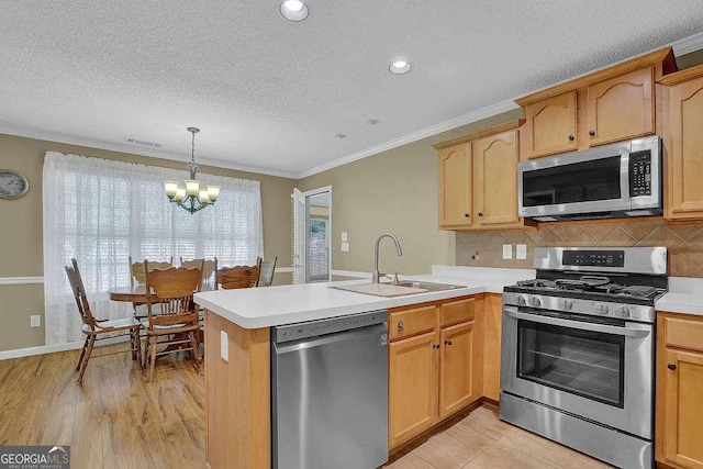 kitchen featuring appliances with stainless steel finishes, a sink, a peninsula, a chandelier, and ornamental molding