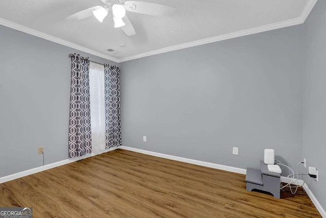 unfurnished room featuring wood finished floors, ceiling fan, baseboards, and crown molding