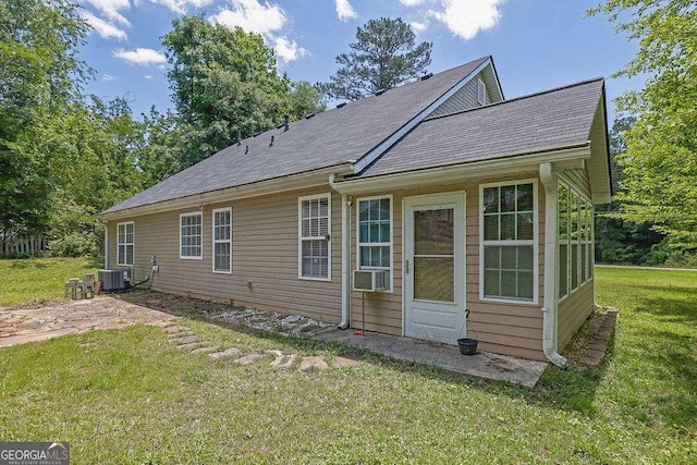 back of house featuring central AC unit, a yard, cooling unit, and a shingled roof
