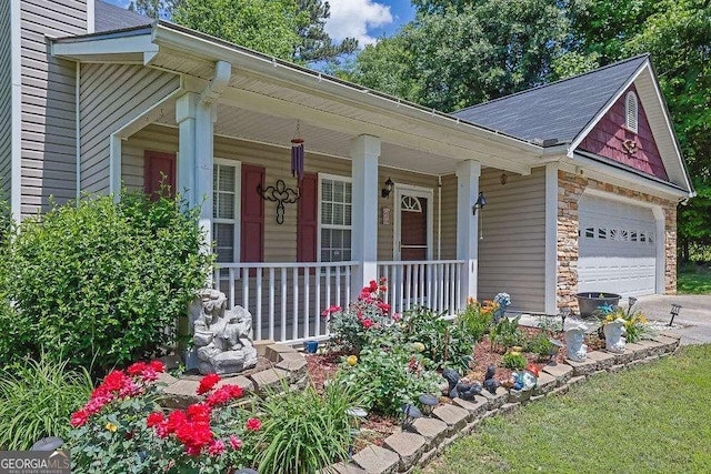 view of front of home featuring a porch, driveway, stone siding, and an attached garage