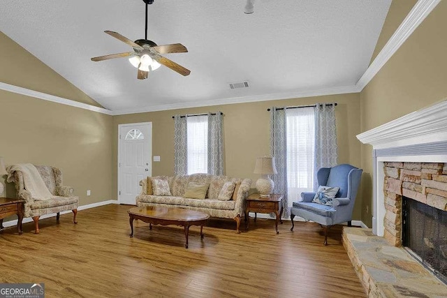 living room with ceiling fan, wood finished floors, a fireplace, vaulted ceiling, and crown molding