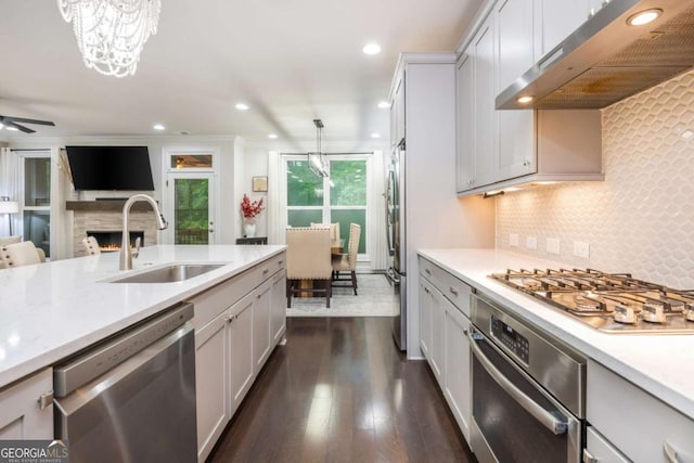 kitchen with appliances with stainless steel finishes, a sink, under cabinet range hood, light countertops, and recessed lighting