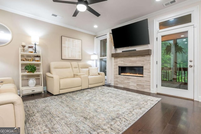 living area with wood finished floors, ceiling fan, ornamental molding, a tile fireplace, and recessed lighting