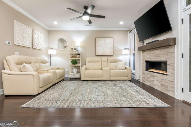 living room with crown molding, a ceiling fan, a tiled fireplace, baseboards, and wood finished floors