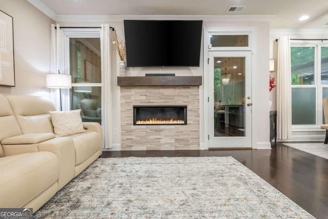 living area with wood finished floors, ornamental molding, a glass covered fireplace, and recessed lighting