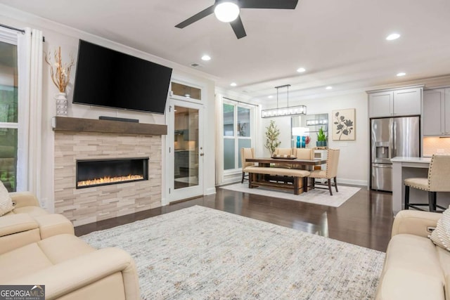 living area with recessed lighting, ceiling fan, dark wood-style flooring, a tiled fireplace, and baseboards