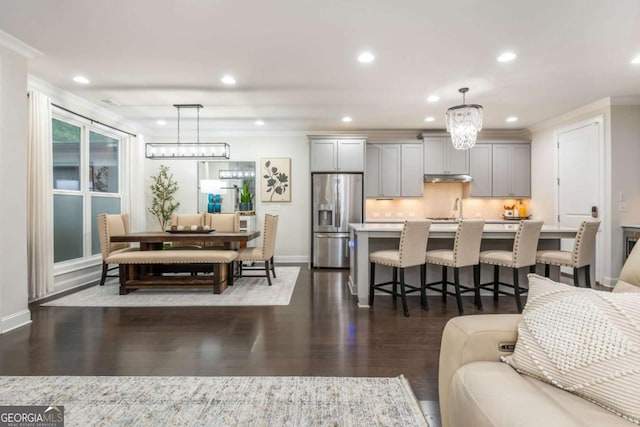 living room featuring recessed lighting, dark wood-type flooring, baseboards, and a chandelier