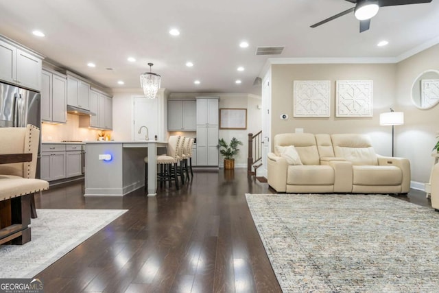 living area featuring ornamental molding, a ceiling fan, dark wood-type flooring, recessed lighting, and baseboards