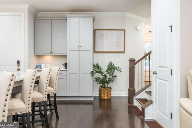 dining space featuring baseboards, dark wood finished floors, crown molding, and stairs