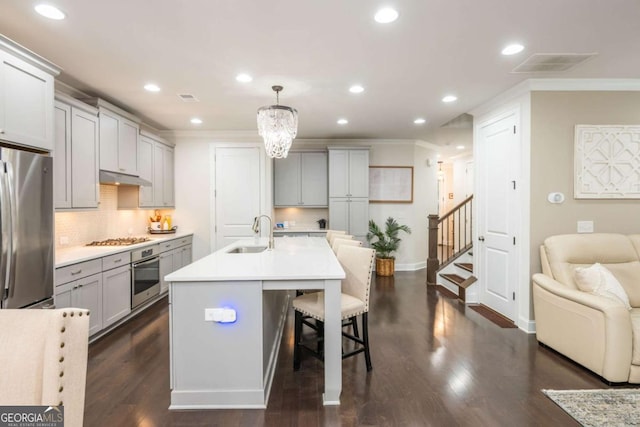 kitchen featuring stainless steel appliances, a sink, under cabinet range hood, ornamental molding, and gray cabinetry